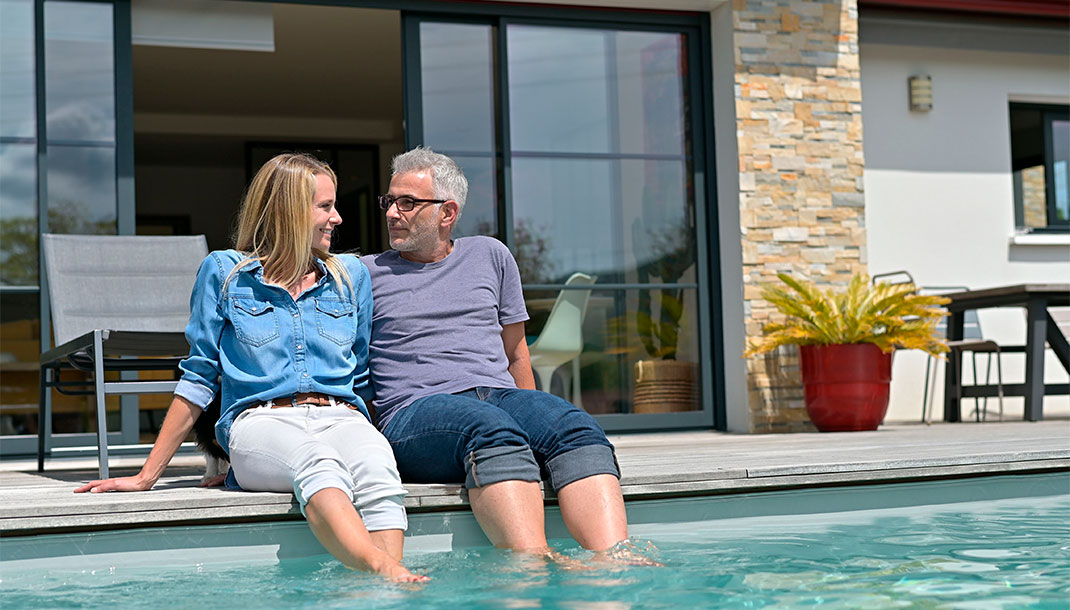 Pareja de esposos disfrutan de piscina privada en su casa